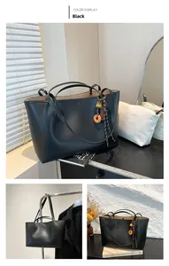 Detail view of large black leather tote bag with stylish lock charm and woven accessories