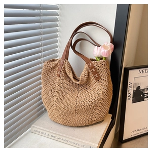 Close-up of woven straw tote bag with leather straps and reinforced stitching details