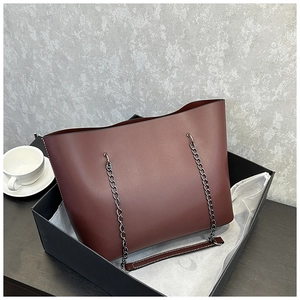 Red-brown leather tote bag with dark metal chain in a black gift box setup