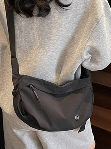 Minimalist black crescent crossbody bag with adjustable strap worn by model in a casual style
