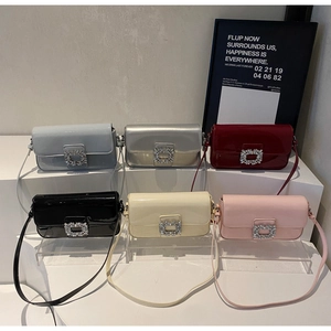 Detail view of stylish crossbody bags in various colors featuring crystal buckles