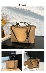 Close-up of khaki leather tote bag with stylish charm pendant and black slim handles