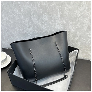 Detail view of large black tote bag with metal chain handles in elegant gift box