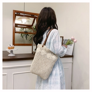 Gros plan du sac fourre-tout tissé crème avec détails crochetés et anses en similicuir marron