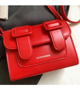 Detailed close-up of the red matte leather flap with decorative dual buckle straps