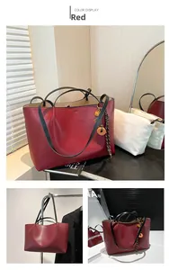 Detail view of large burgundy tote bag with gold heart charm and canvas inner bag insert
