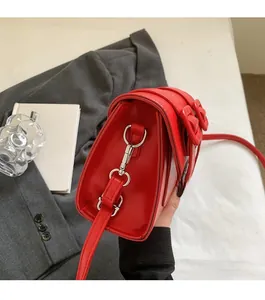 Detail of red glossy leather crossbody bag featuring polished silver metal hardware