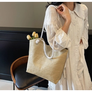 Detail of woven straw tote bag with white rope handles and tulip flowers for summer style