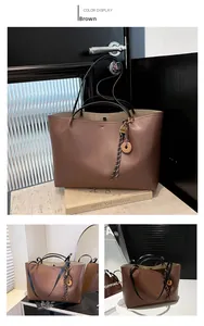 Detail view of large brown tote bag with dual handles and stylish tassel charm decoration