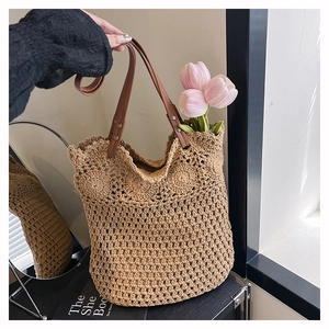 Détail d'un sac cabas en paille tissé à la main avec bordure festonnée et lanières en cuir