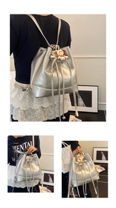 Detail of silver metallic bucket bag with drawstring closure and cute cat charm accessory