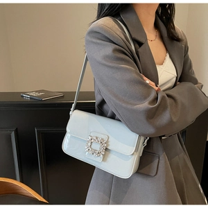 Close-up of the large sparkling crystal square buckle on a light blue patent leather bag