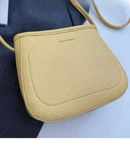 Close-up of yellow lychee grain leather crossbody bucket bag with fine stitching
