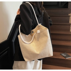 Close-up of woven straw tote bag featuring thick cotton rope handles and fine texture
