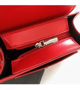 Detail of high-quality silver metal zipper on red leather crossbody bag interior
