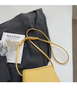 Detailed close-up of yellow leather bucket bag featuring unique braided strap detail