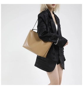 Detail of camel leather tote bag with black straps worn with a stylish blazer