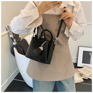 Vue détaillée du sac seau en cuir noir grainé avec pendentif en cœur et détails argentés