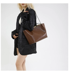 Brown leather tote bag styled on model with black shoulder straps and spacious design