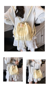Detail view of cream drawstring bucket bag in polished PU leather with cute cat pendant