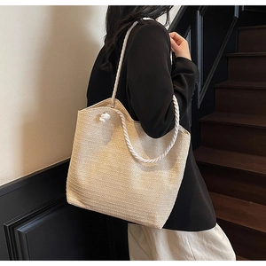 Detailed close-up of beige woven straw tote bag with white cotton rope handles