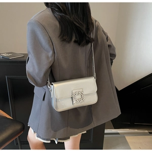 Detailed close-up of a silver mirror leather shoulder bag with a large sparkling rhinestone buckle