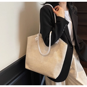 Detail of handwoven straw tote bag with white rope handles for casual beach style