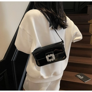 Close-up of black patent leather underarm bag featuring a luxury rhinestone square buckle
