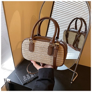Detailed view of woven straw bucket bag with brown leather trim and reflection