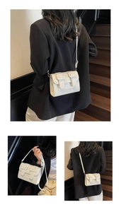 Detailed view of a white leather crossbody bag with dual buckles and adjustable shoulder strap