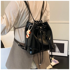 Detail of black patent leather bucket backpack with drawstring bow and cute bunny charm