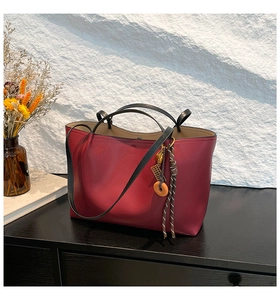 Detail of burgundy leather tote bag with elegant tassels and golden lock charms