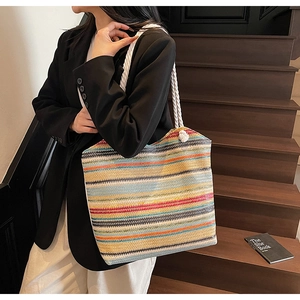 Detail of colorful woven straw tote bag with thick white rope handles on stairs