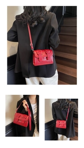 Detail showing the red glossy PU leather shoulder bag with adjustable straps and buckles