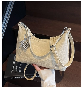 Detail view of cream white shoulder bag with pebble texture and silver heart charm