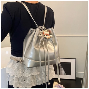 Detail of silver bucket backpack with drawstring closure and cute doll charm accessory