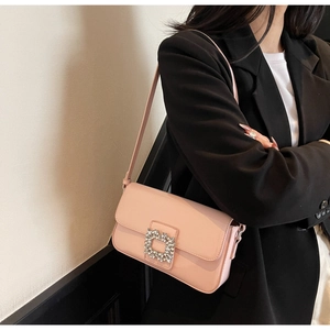 Detailed view of pink patent leather shoulder bag with crystal square buckle and strap