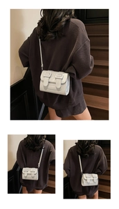 Detail view of a white mini flap crossbody bag with square buckle accents and leather strap