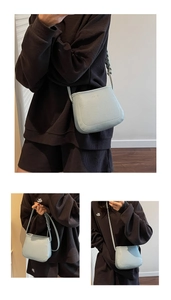 Detail of light blue crossbody bag with unique braided strap and litchi grain texture