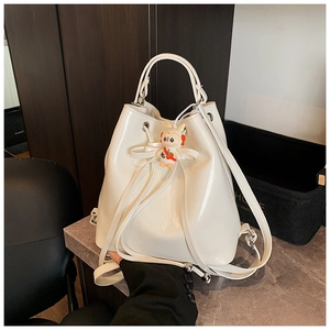 Close-up of a white patent leather bucket bag featuring a cute bunny charm and bow detail