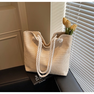 Detailed macro view of woven straw tote bag with sturdy cotton rope handles and metal eyelets