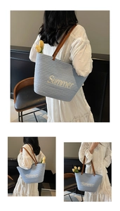 Detail of the sky blue straw woven tote bag with yellow Summer embroidery and leather handles