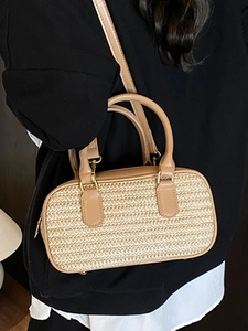 Fashionable straw woven crossbody bag with tan leather handles and gold zipper detail