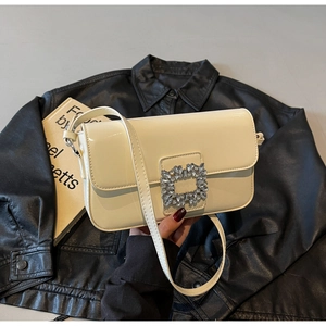 Detail of a creamy white glossy leather bag featuring a large square rhinestone buckle