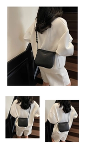 Close-up of black textured leather crossbody bucket bag with white logo and thin strap