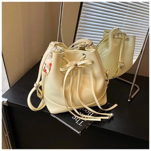 Detail of cream drawstring bucket bag with cute sheep charm and smooth PU leather finish