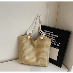 Detail of hand-woven straw tote bag with white cotton rope handles and fine texture
