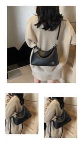 Detail of black lychee grain leather crossbody bag with silver pearl charm and logo