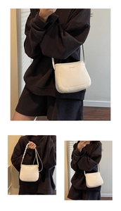 Detail of white lychee pattern leather bucket bag with brand logo and slender shoulder strap