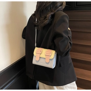 Detailed view of a pastel multi-color leather satchel bag on a model wearing dark suit